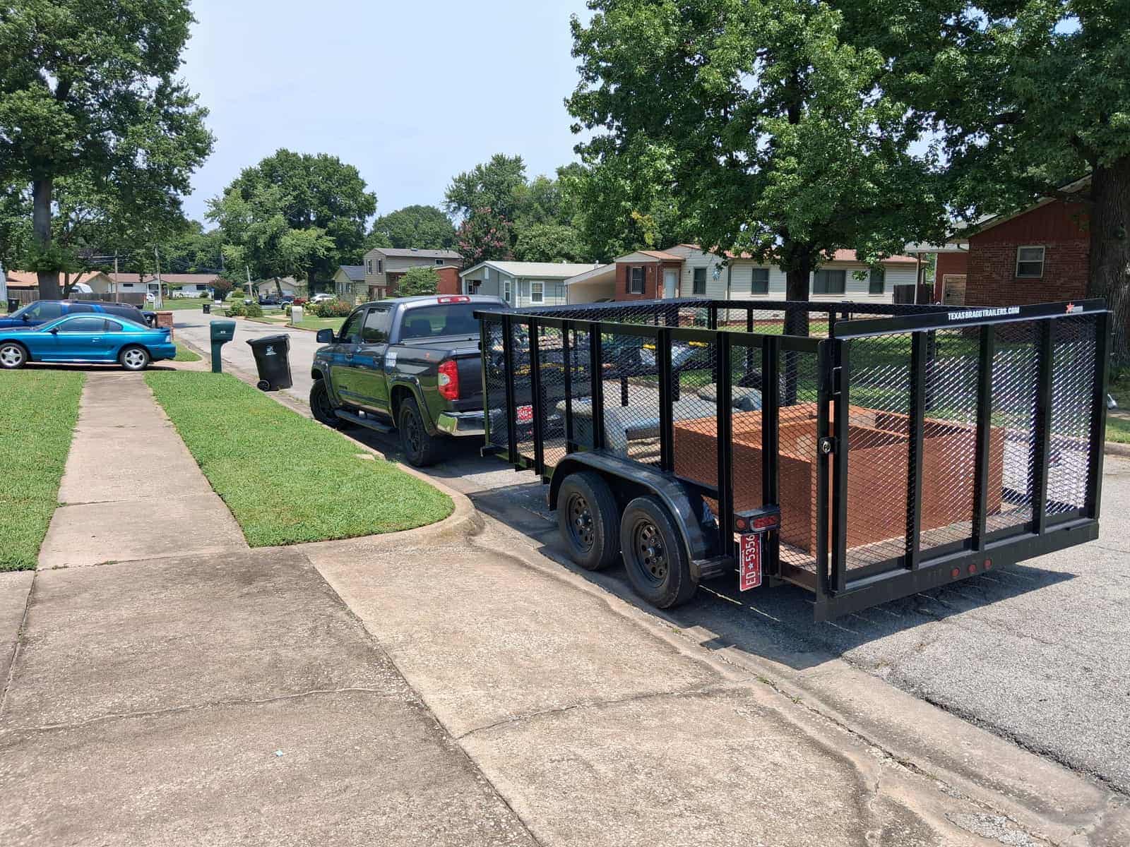 The JunkLimo trailer parked at a Tulsa kerb loaded with stacked wooden furniture panels